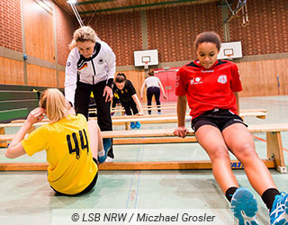 Trainerin leitet eine Sportgruppe beim Zirkeltaining an