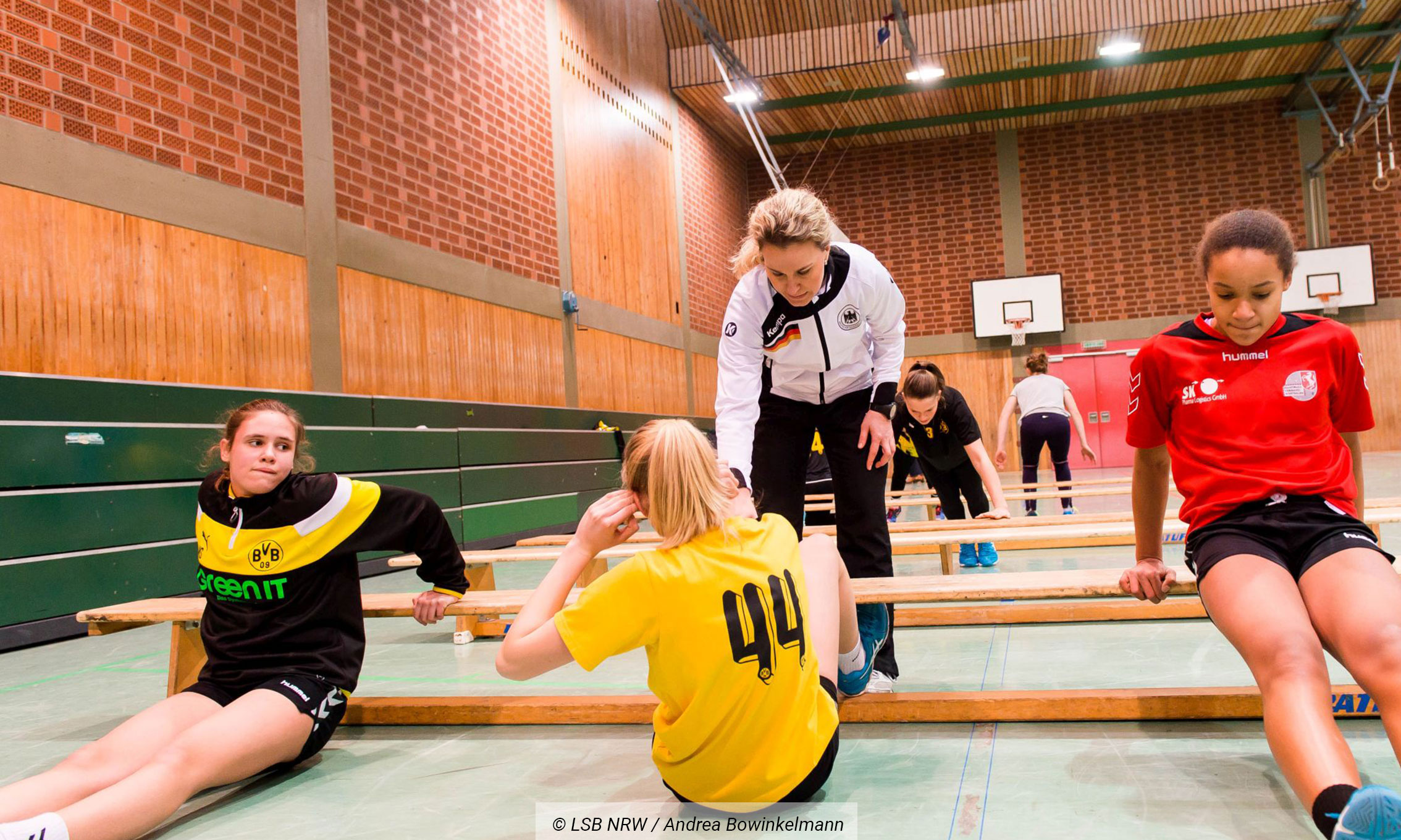 Eine Trainerin leitet eine Gruppe junger Sportlerinnen in einem Zirkeltraining an
